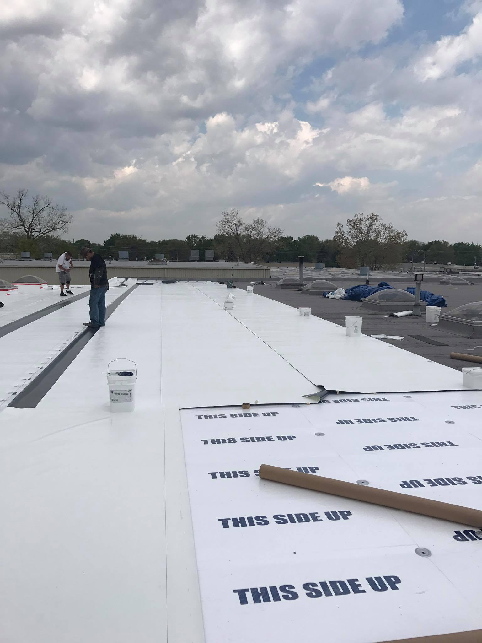 Crew working on white membrane layout on a flat roof